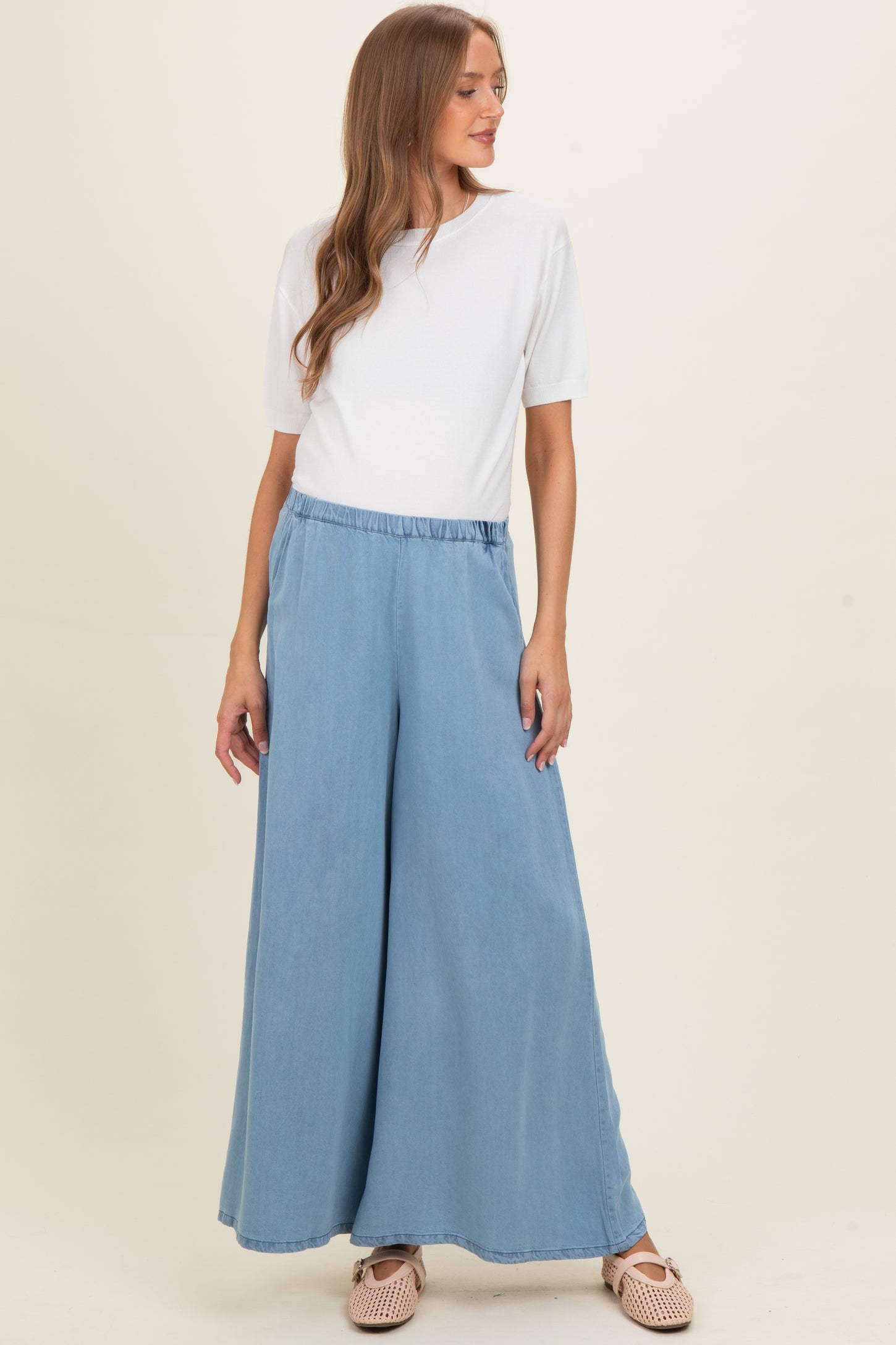 woman wearing a white short sleeve top and light blue wide leg maternity pants