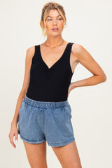 woman wearing a black maternity tank top with a v-neck and light blue denim maternity shorts