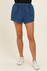 woman wearing blue denim shorts with an elastic waistband and side pockets, paired with white sneakers