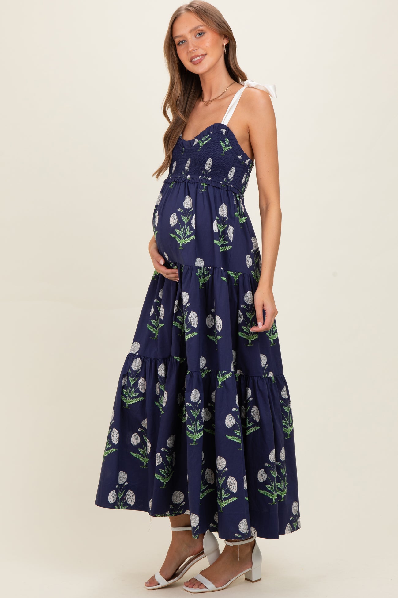 woman wearing a navy floral maternity maxi dress with a tiered skirt and adjustable straps, showcasing her baby bump