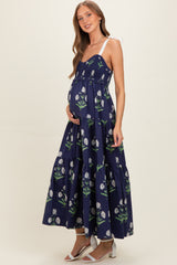 woman wearing a navy floral maternity maxi dress with a tiered skirt and adjustable straps, showcasing her baby bump