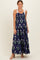 woman wearing a navy floral maxi dress with tie shoulder straps and a tiered skirt