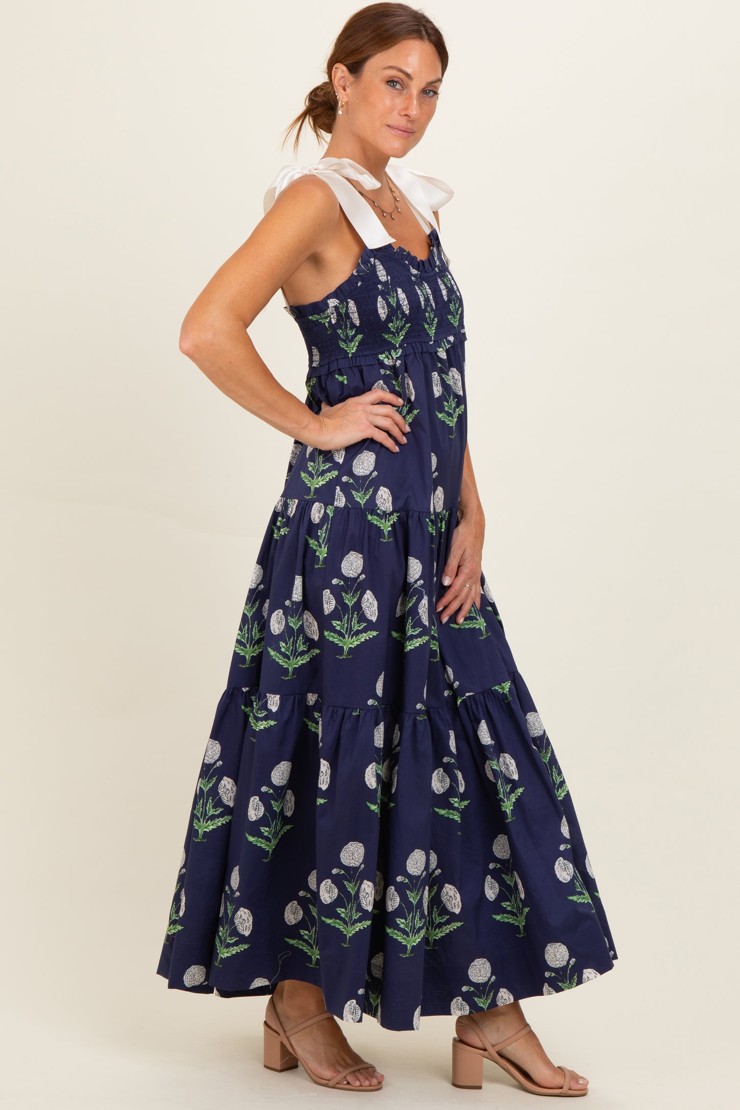 woman wearing a navy blue floral maxi dress with a tiered skirt and white shoulder straps