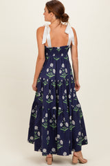 woman wearing a navy blue floral maxi dress with tie straps and a tiered design, shown from the back