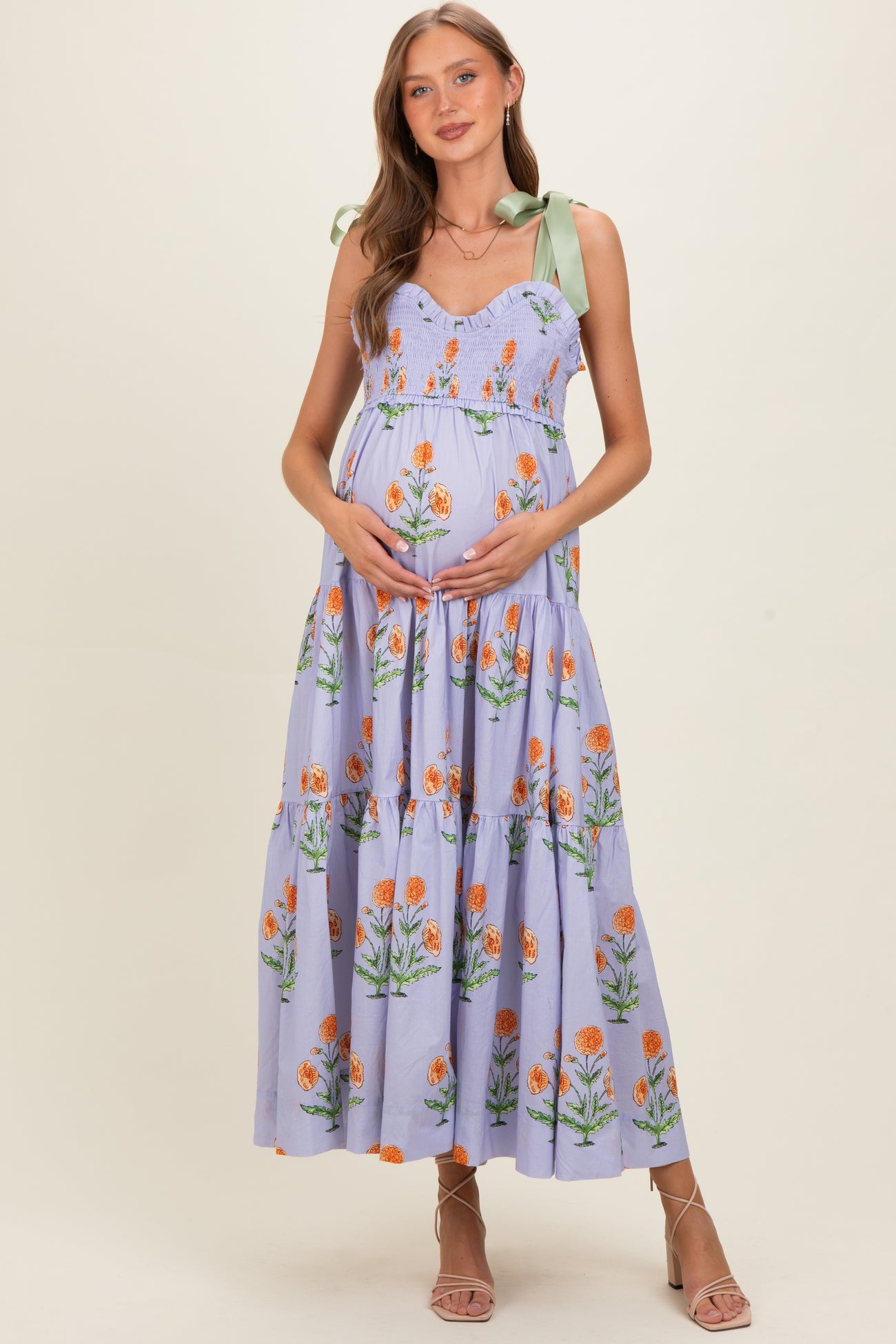 woman wearing a lavender floral maternity maxi dress with tie straps and holding her baby bump