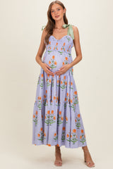 woman wearing a lavender floral maternity maxi dress with tie straps and holding her baby bump