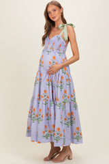 woman wearing a lavender floral maternity maxi dress with adjustable green ribbon straps and a visible baby bump
