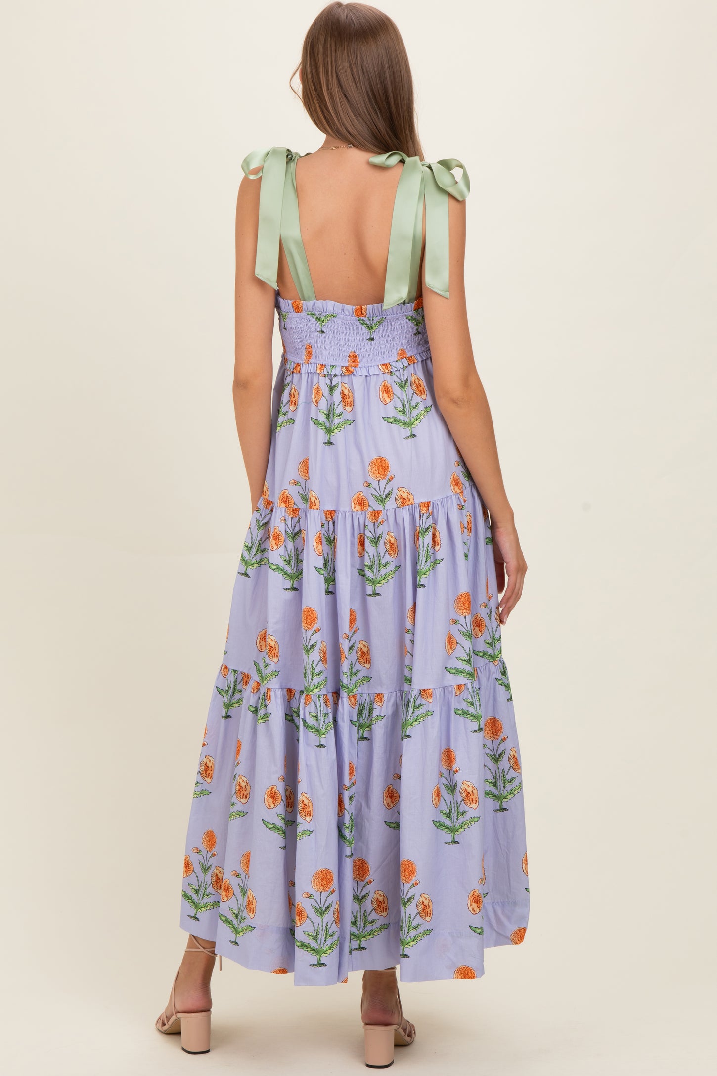 woman wearing a lilac floral maternity maxi dress with back cutout and green ribbon tie straps