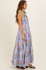 woman wearing a lavender floral maxi dress with green tie straps and a tiered skirt