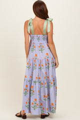 woman wearing a purple floral maxi dress with green tie straps, showing tiered design and back details