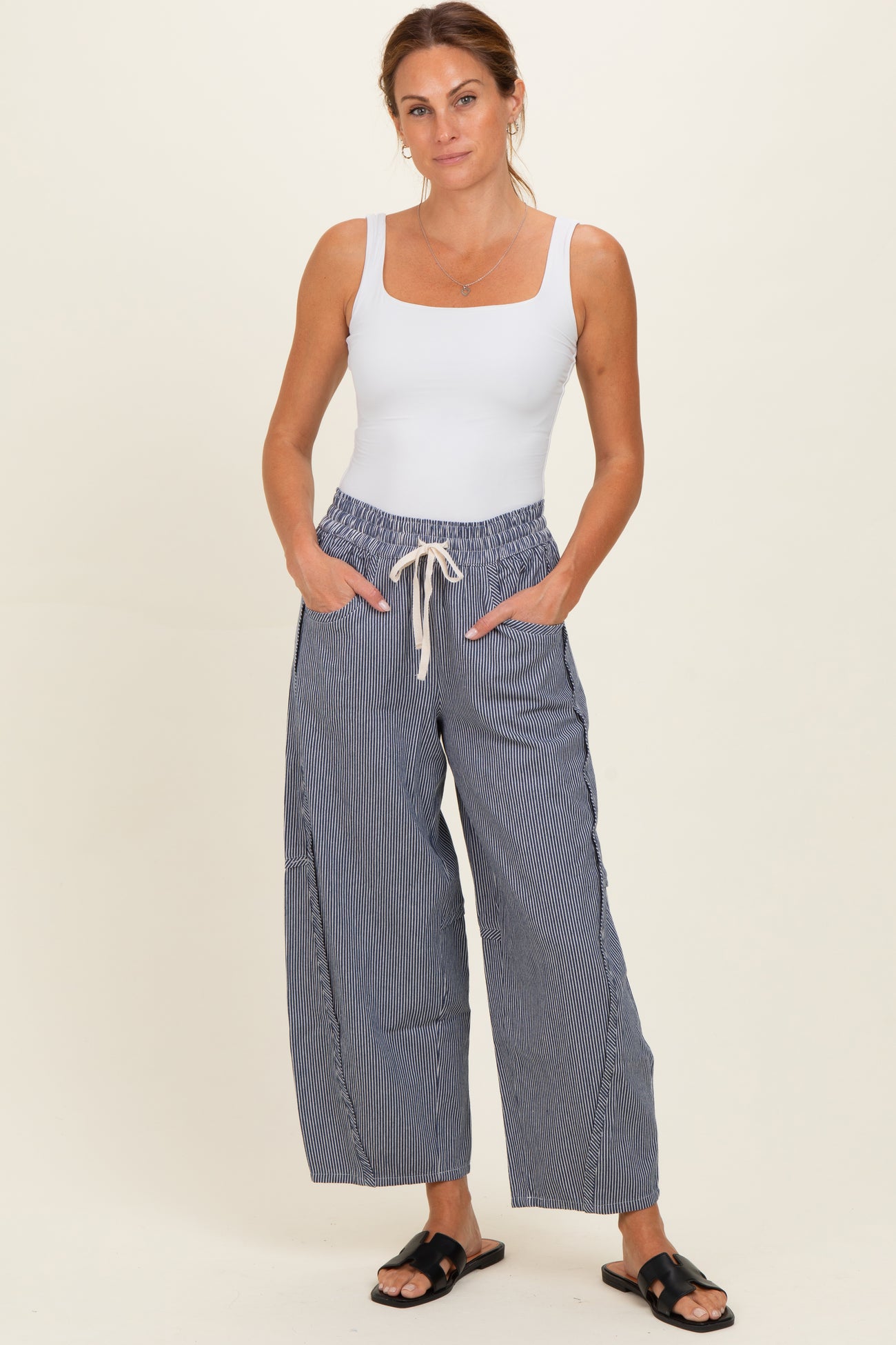 woman wearing a white fitted tank top and navy striped wide-leg pants with drawstring waist and side pockets