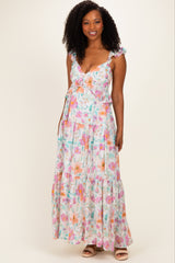 woman wearing a floral maxi dress with ruffles and a tie front, featuring pastel colors and a tiered skirt