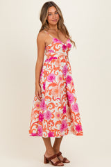woman wearing a floral print midi dress in orange and pink with spaghetti straps and a fitted waist