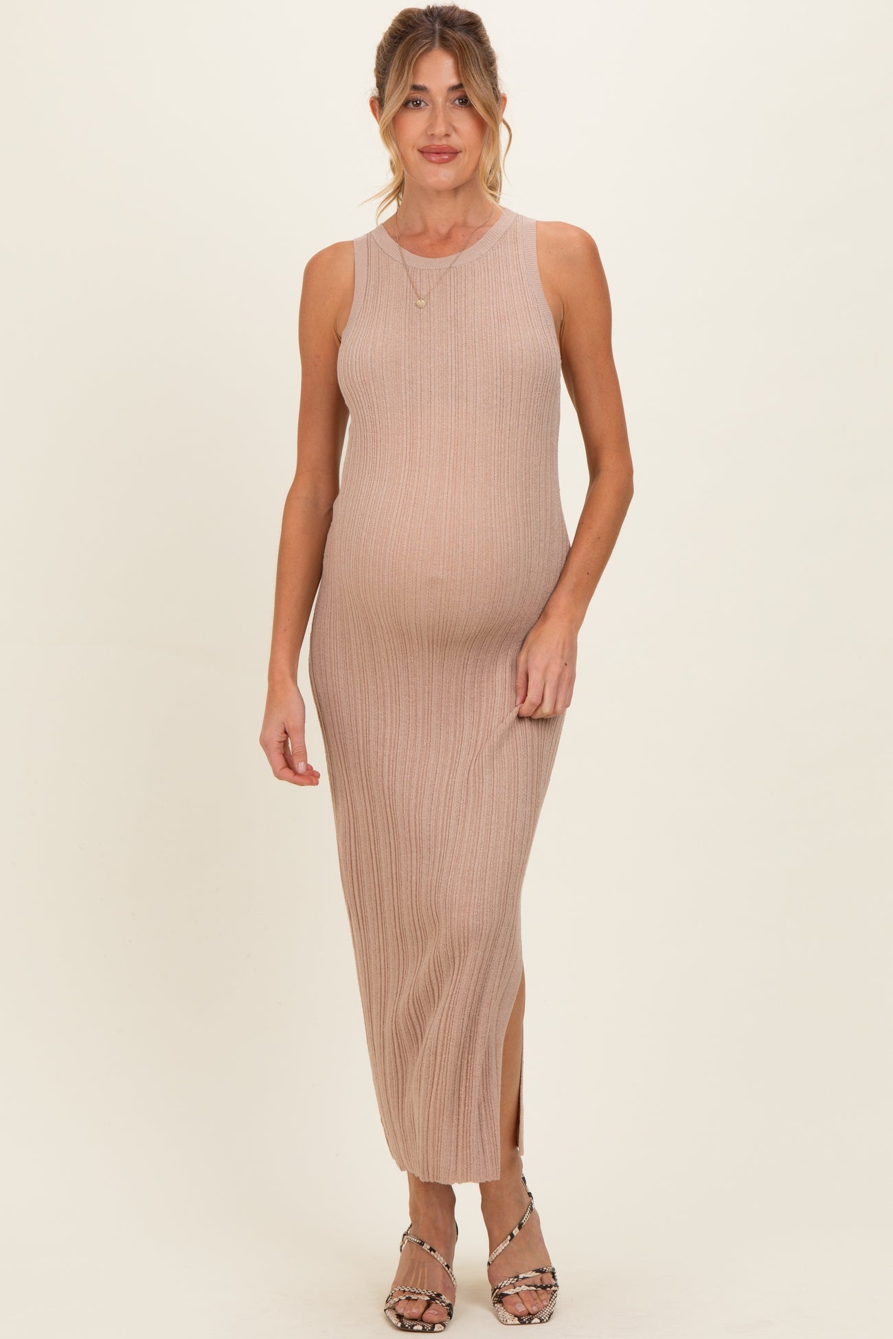 woman wearing a beige ribbed maternity maxi dress with side slits and a visible baby bump