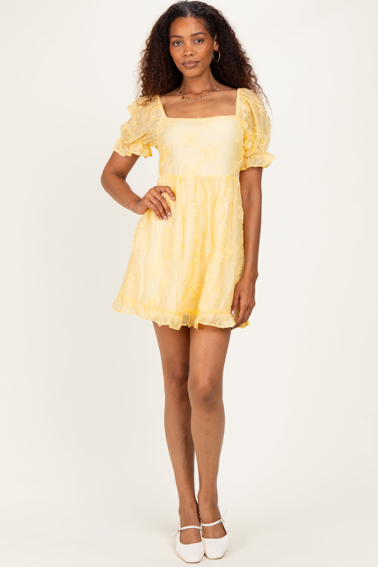 woman wearing a yellow short puff sleeve dress with a square neckline and a flared skirt