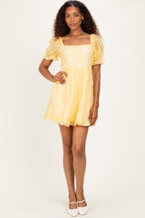 woman wearing a yellow short puff sleeve dress with a square neckline and a flared skirt
