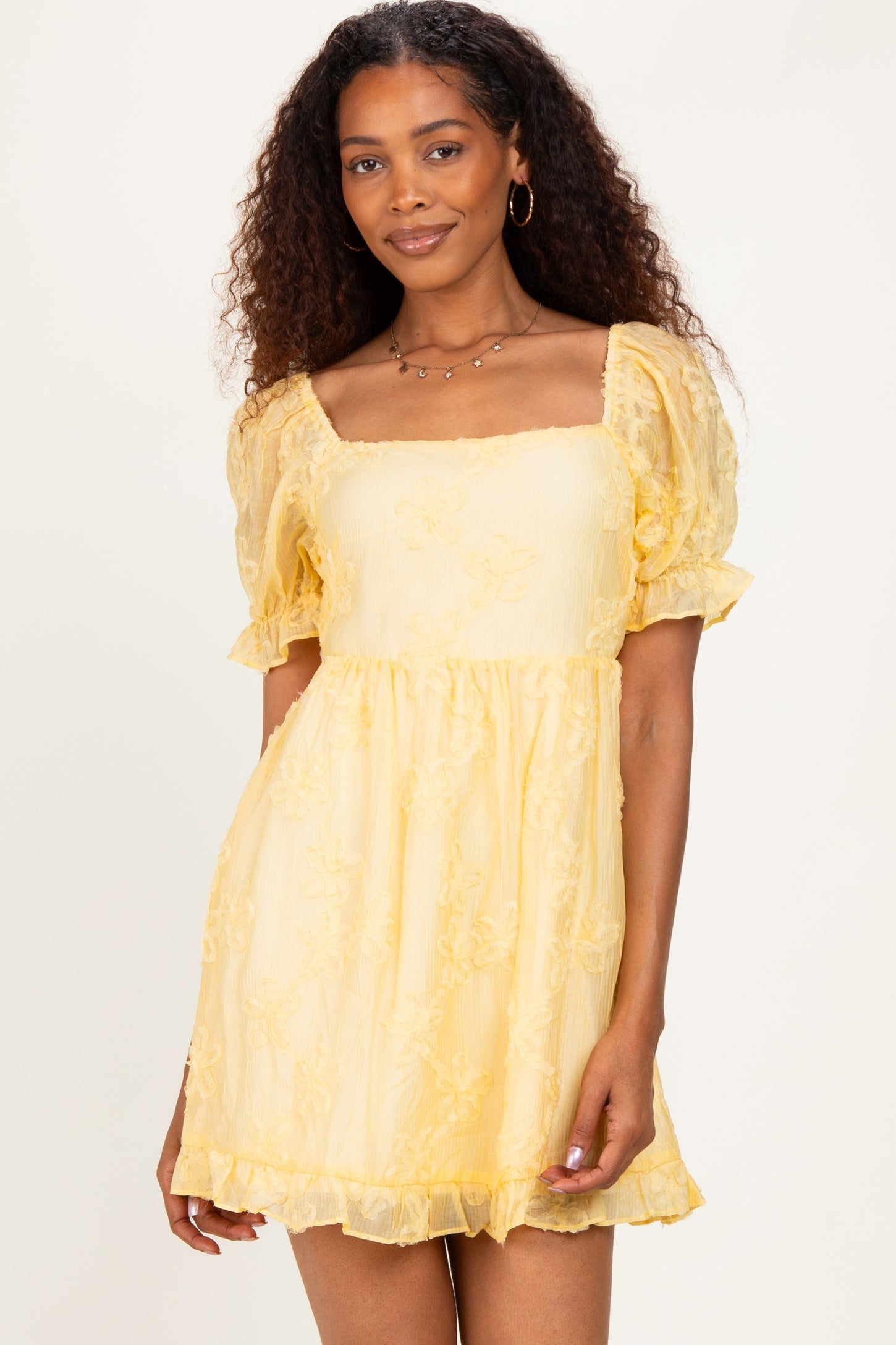 woman wearing a yellow short puff sleeve dress with a square neckline and floral embroidery