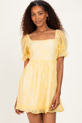 woman wearing a yellow short puff sleeve dress with a square neckline and floral embroidery