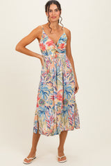 woman wearing a floral print midi dress with a deep v-neck and spaghetti straps, standing with one hand on her hip
