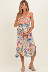 woman wearing a colorful floral maternity dress and holding her baby bump