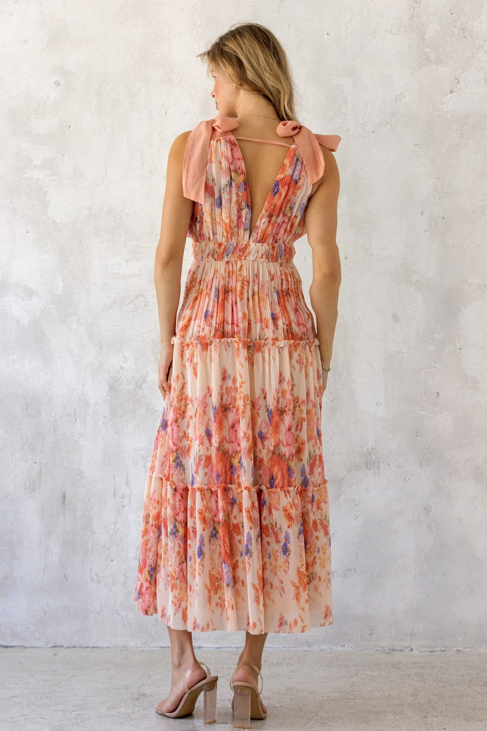 woman wearing a floral tiered maxi dress with a smocked bodice and bow shoulder straps, view from the back