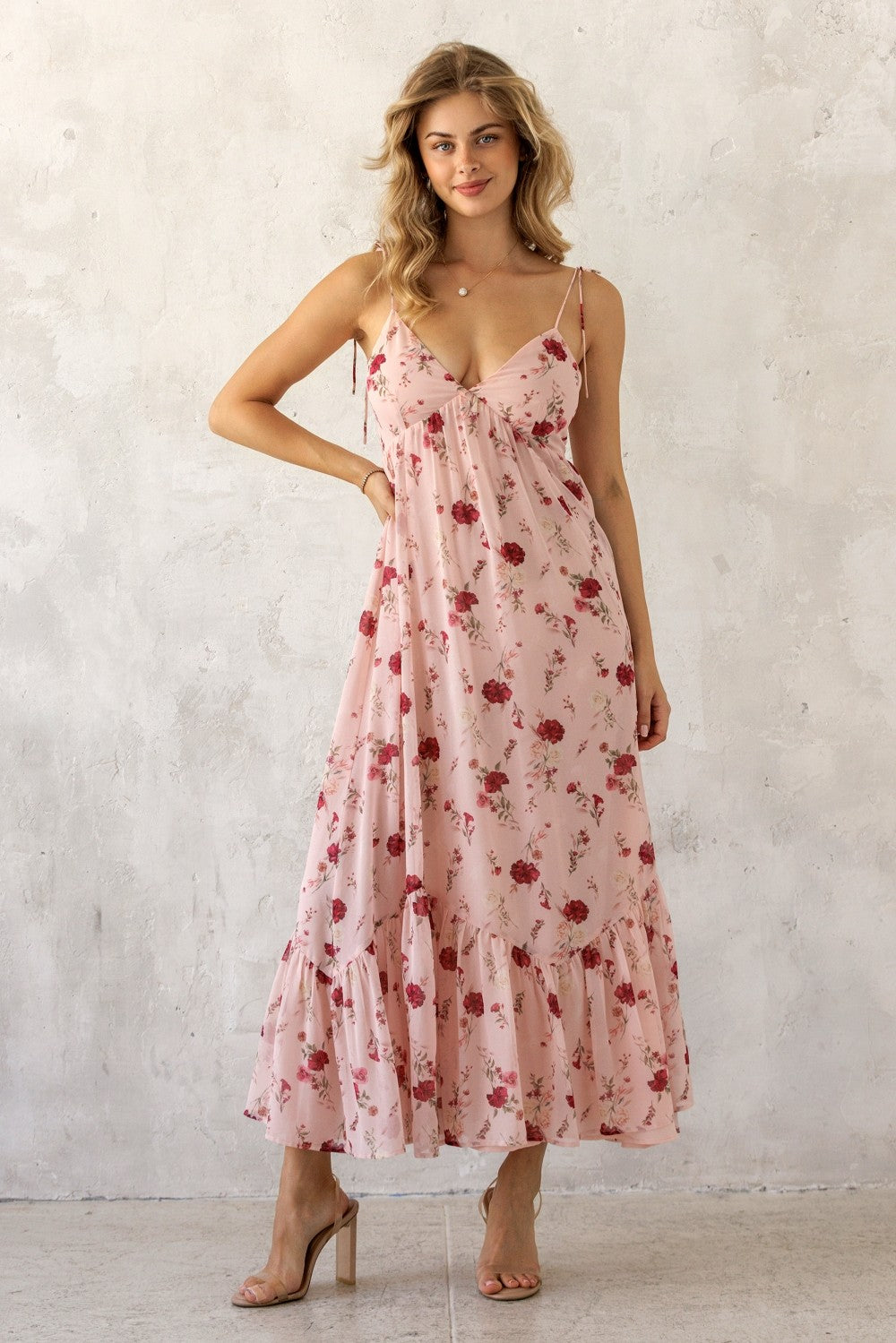woman wearing a pink floral maxi dress with spaghetti straps and ruffled hem