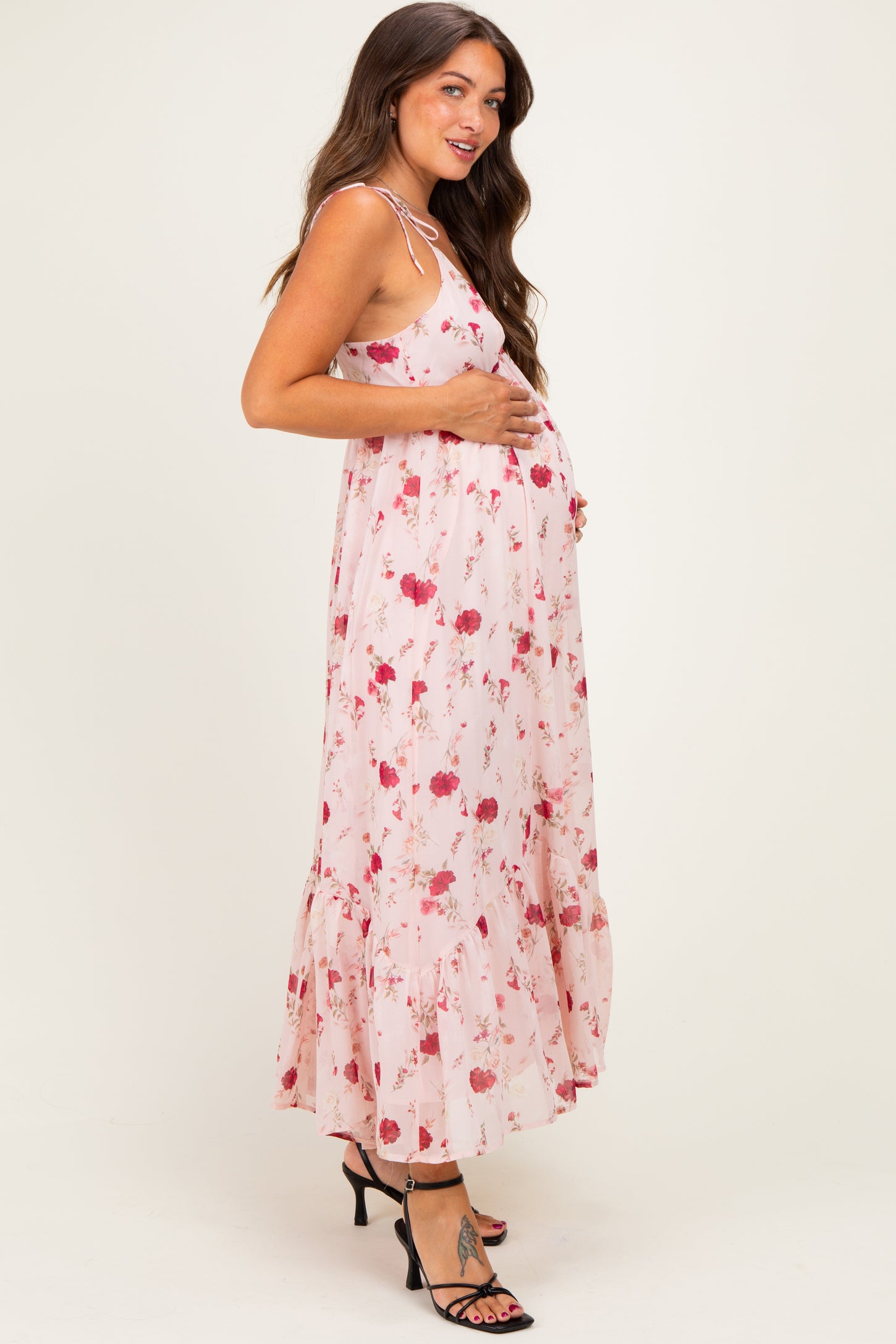 woman wearing a pink floral maternity maxi dress and holding her baby bump
