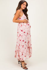 woman wearing a pink floral maternity maxi dress and holding her baby bump