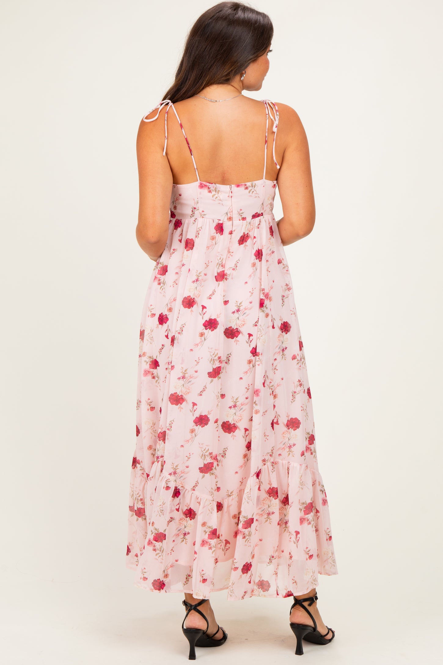 woman wearing a pink floral maternity maxi dress with back ties and ruffle hem
