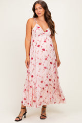 woman wearing a pink floral maternity maxi dress with adjustable straps and a flowing skirt, highlighting her baby bump