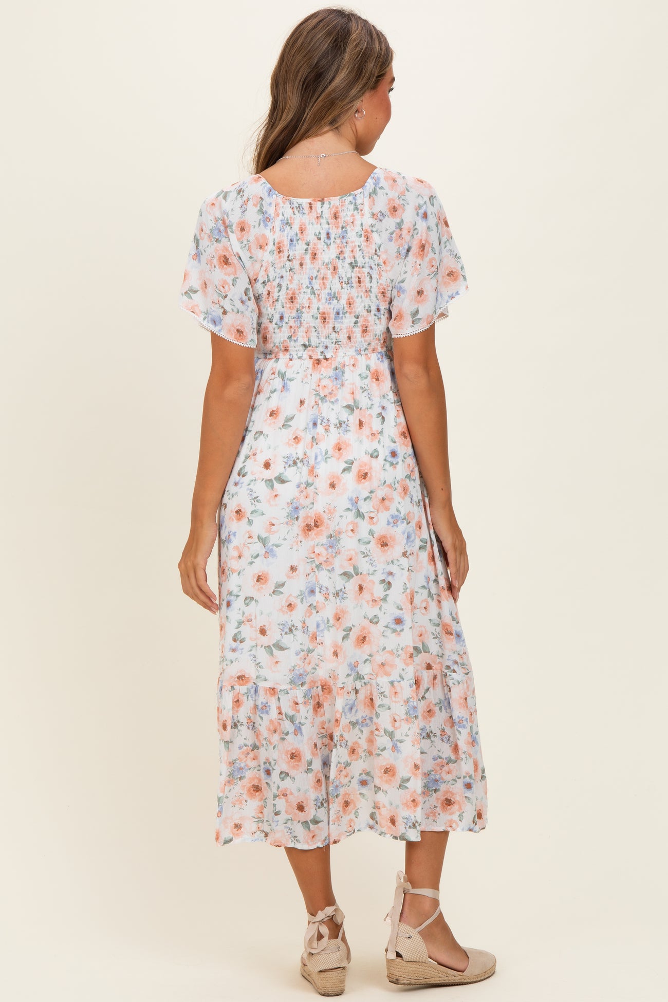 woman wearing a floral midi dress with short sleeves and a tiered skirt, shown from the back