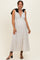woman wearing a white polka dot maternity dress with a deep V-neck and black bow straps