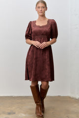 woman wearing a burgundy floral print puff sleeve dress paired with knee-high brown leather boots