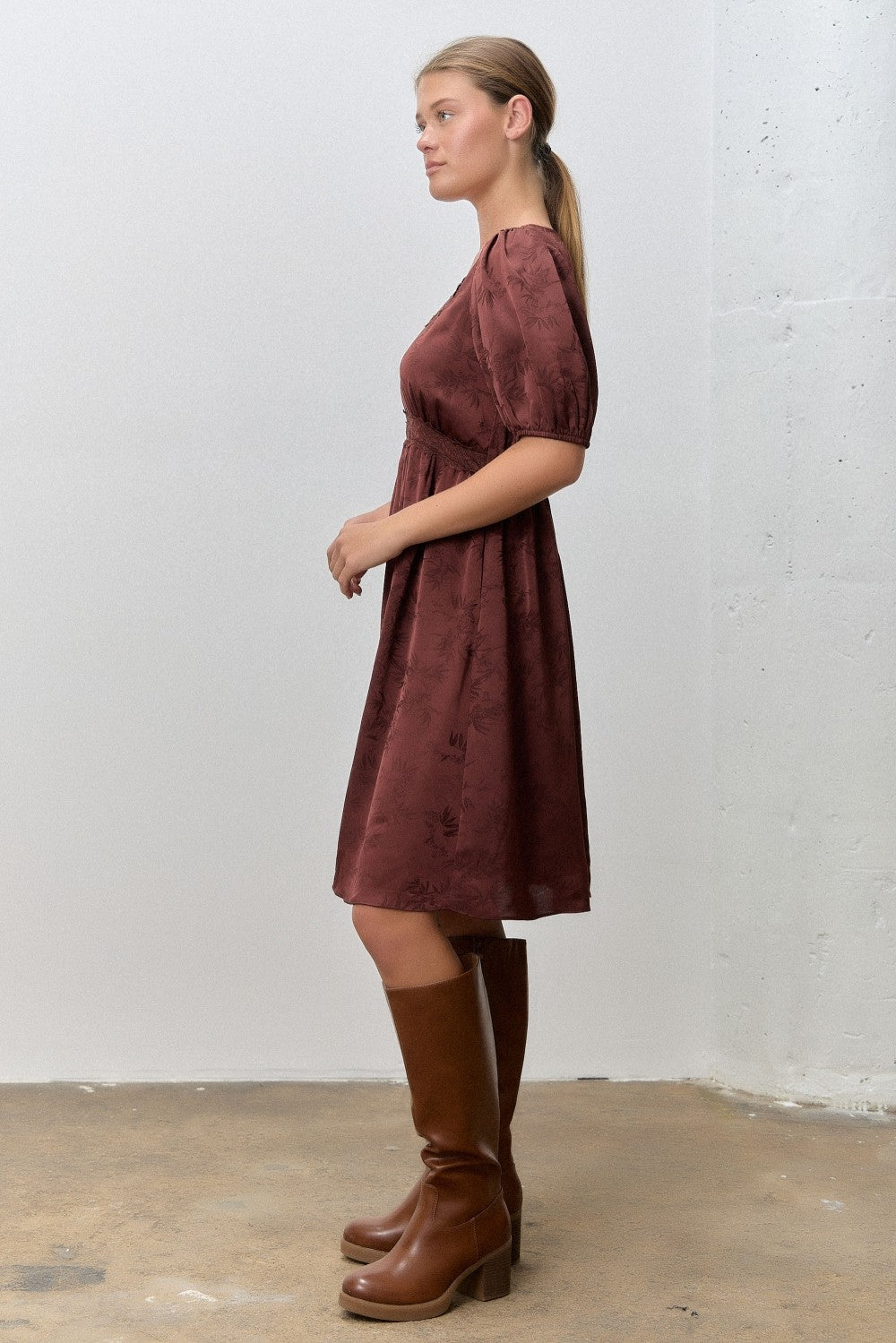 woman wearing a burgundy floral print dress with puff sleeves and brown knee-high boots
