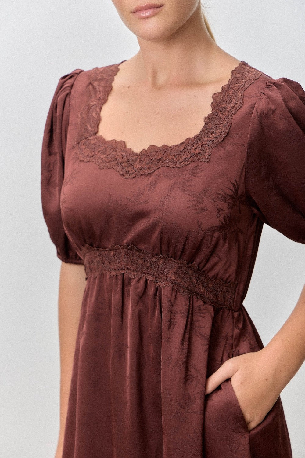 woman wearing a brown short sleeve dress with lace detailing and a fitted waist, featuring pockets