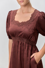 woman wearing a brown short sleeve dress with lace detailing and a fitted waist, featuring pockets