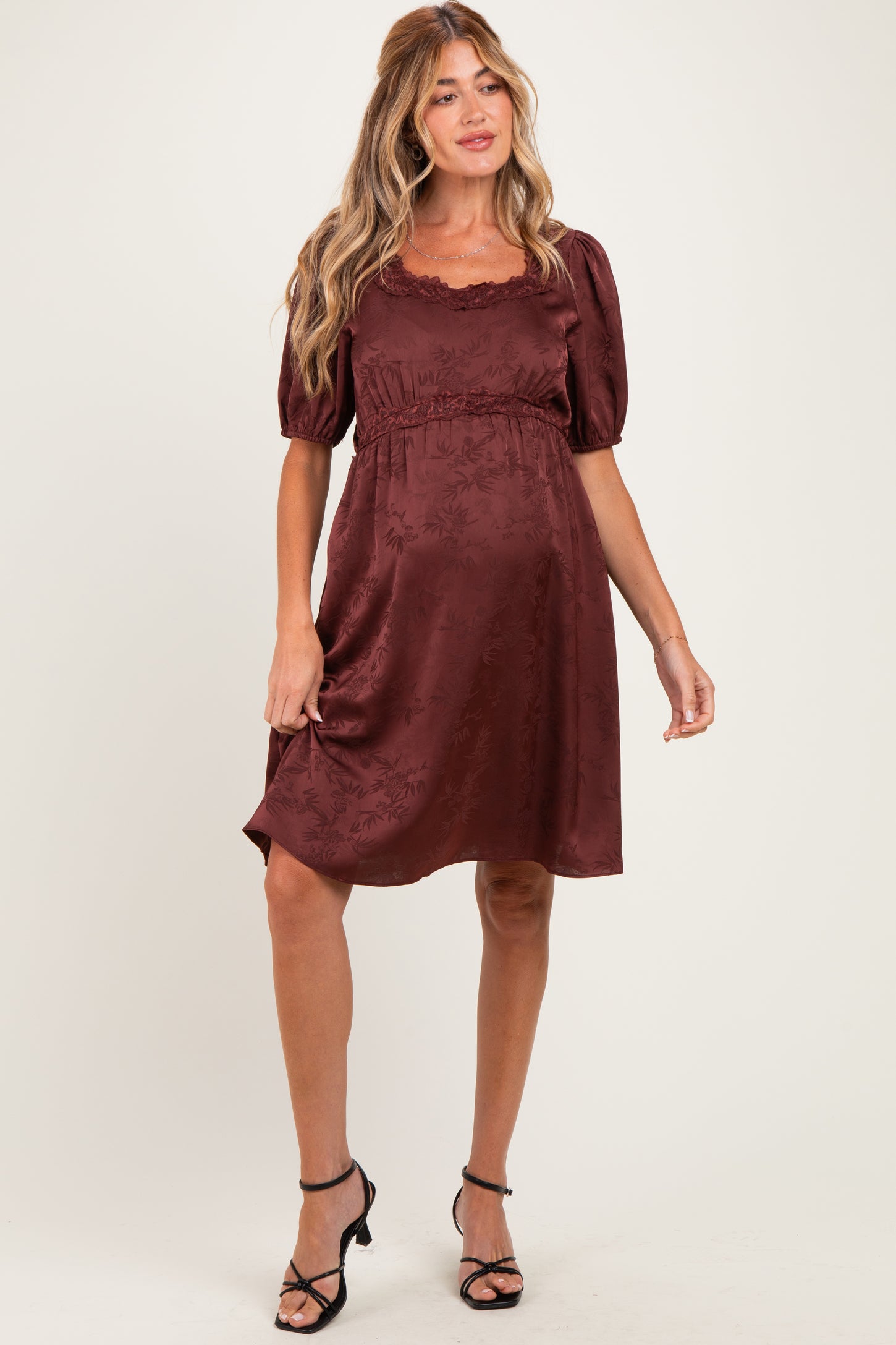 woman wearing a burgundy floral maternity dress with puff sleeves and a cinched waist, showcasing her baby bump