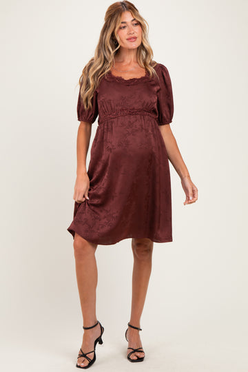 woman wearing a burgundy floral maternity dress with puff sleeves and a cinched waist, showcasing her baby bump