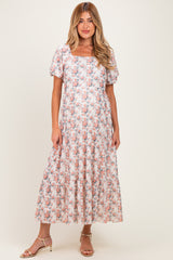 woman wearing a floral maternity maxi dress with short sleeves and a square neckline, showcasing her baby bump