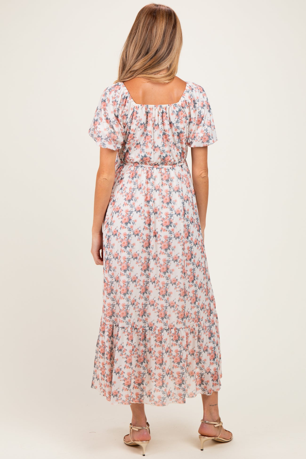 woman wearing a floral maternity maxi dress with short sleeves and a fitted waist clasp at the back