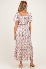 woman wearing a floral maternity maxi dress with short sleeves and a fitted waist clasp at the back