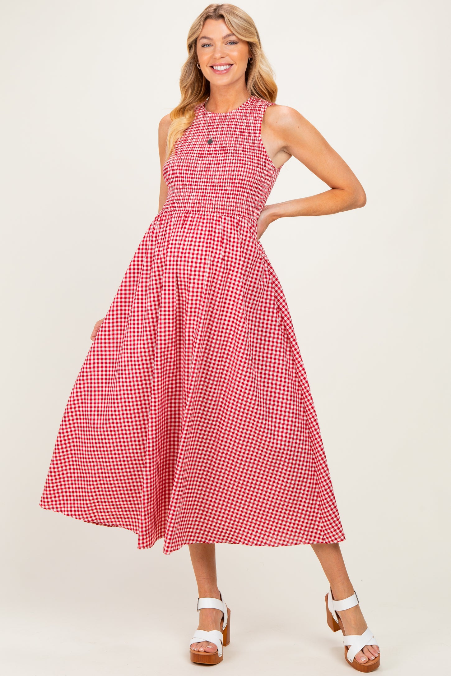 woman wearing a red and white gingham maternity dress with a fitted bodice and flowy skirt, showcasing her baby bump