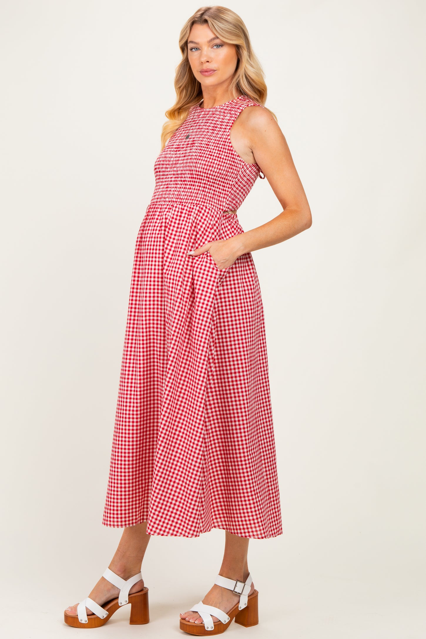 woman wearing a red and white gingham maternity dress with a smocked bodice and pockets