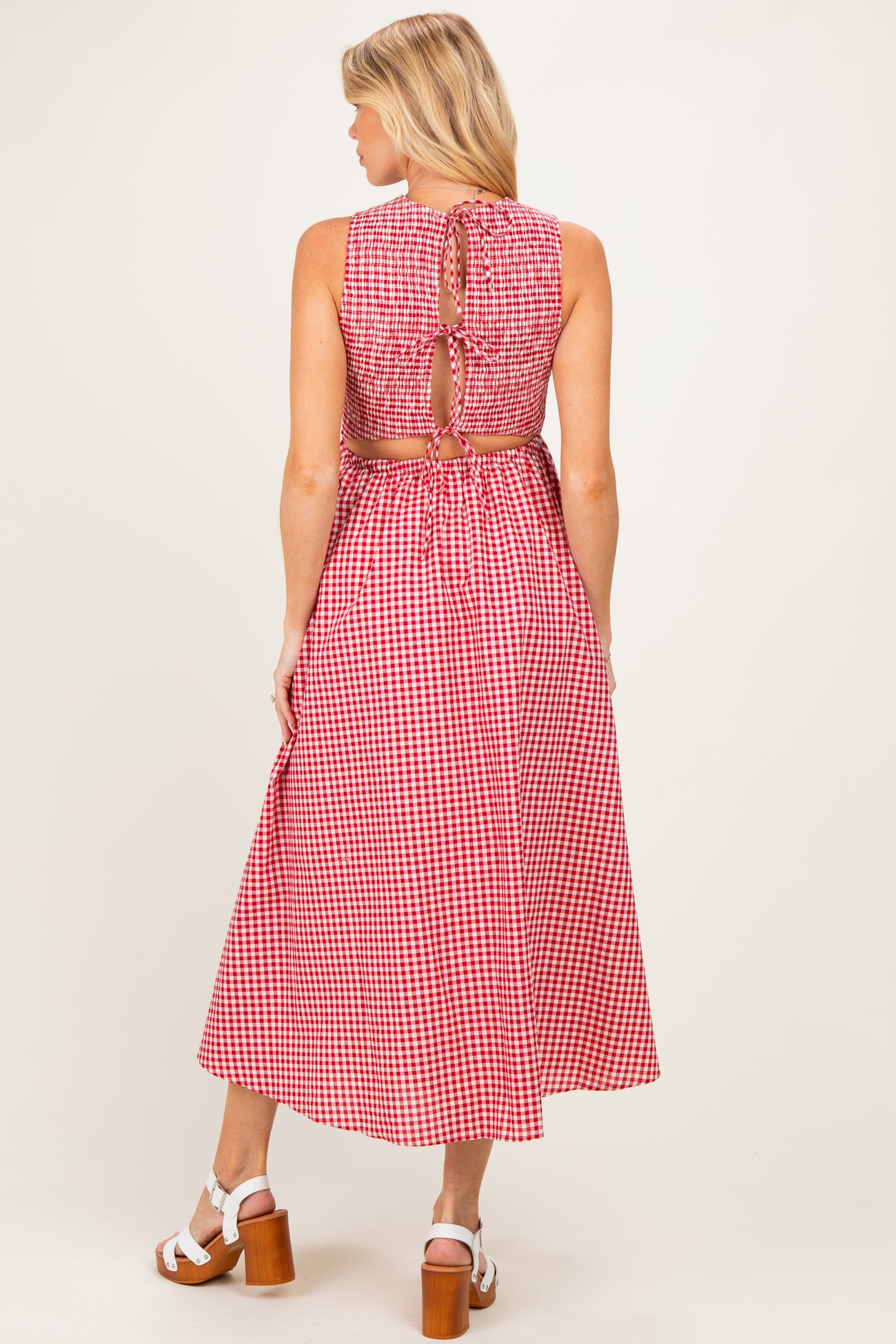 woman wearing a red and white gingham maternity dress with an open back and a cinched waist