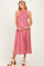woman wearing a red and white gingham maternity dress with a smocked bodice and holding her baby bump