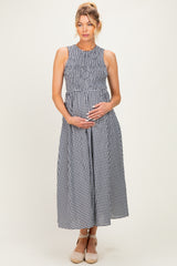 woman wearing a black and white gingham maternity dress with a smocked bodice and holding her baby bump