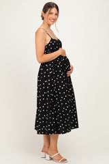 woman wearing a black polka dot maternity dress and holding her baby bump