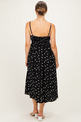 woman wearing a black polka dot maternity midi dress with adjustable straps and a smocked back, view from the back