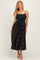 woman wearing a black midi dress with white polka dots and adjustable spaghetti straps