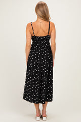 woman wearing a black midi dress with white polka dots and smocked back detail, shown from the back